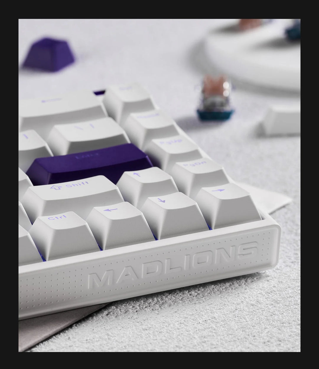Close-up of a white keyboard with purple keycaps on a light gray surface.